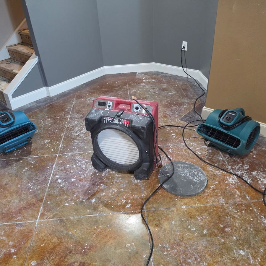 HEPA air scrubber running between two air movers on a stained concrete floor