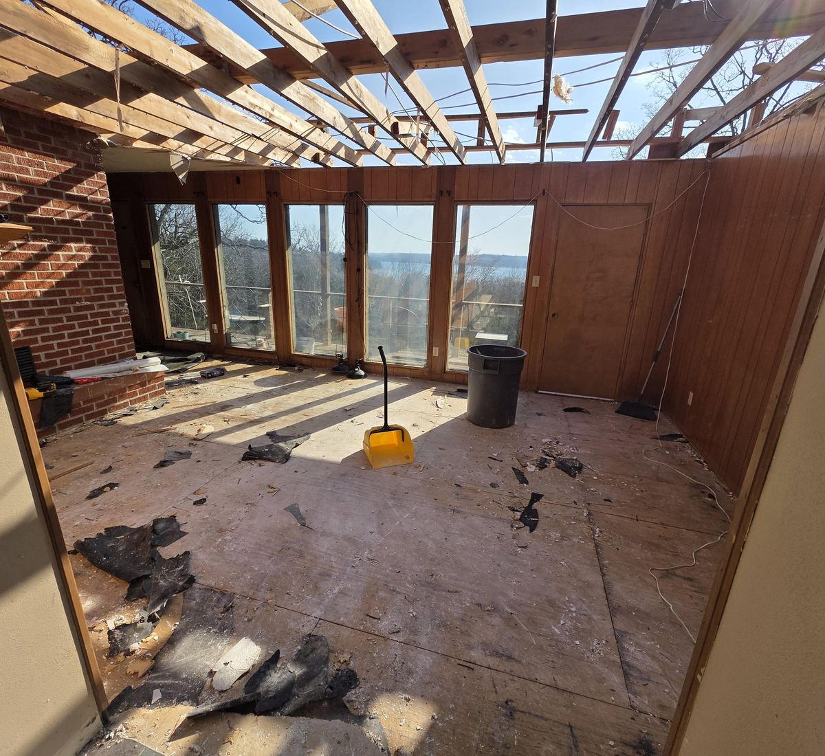 Storm-damaged lake house sunroom gutted to the rafters, open to the sky, mid-dry