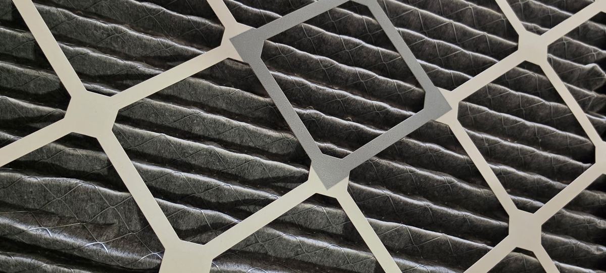 Soot-blackened HVAC filter held up to the light after a fire